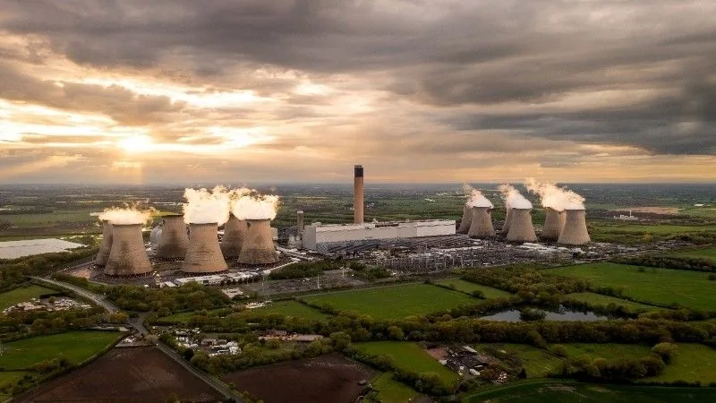Aerial view of a coal-fired power plant with smoke rising from stacks.