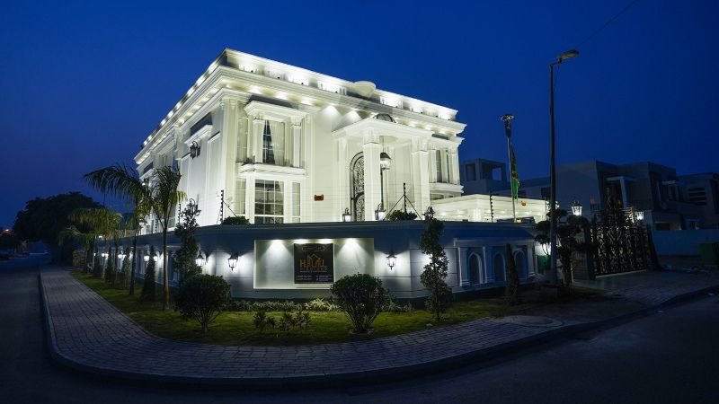 A luxurious white mansion in Bahria Town, Lahore, designed with modern architecture, elegant lighting, and a landscaped garden at night, built by the best builders in Lahore for luxury homes.