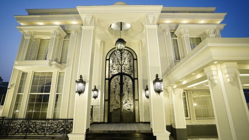 "Elegant exterior of a luxury home with intricate iron gate, grand columns, and modern lighting, showcasing Complete House Construction Solutions in Lahore.