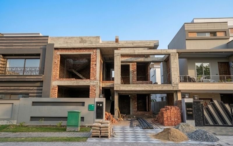 Grey Structure Construction Services in Lahore for a modern double-story house under construction with concrete frame and brick walls.