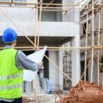 Construction professionals reviewing a building project plan on-site, emphasizing the importance of timely project delivery in construction.