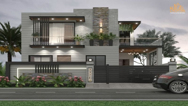 A modern double-story house in Lahore designed by an expert Architecture & Interiors Designer House Builder in Lahore. The home features sleek contemporary elements, large glass windows, stylish lighting, and a landscaped front yard with vibrant greenery.