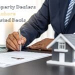 A professional property dealer signing real estate documents beside a model house, representing trusted property deals in Lahore.