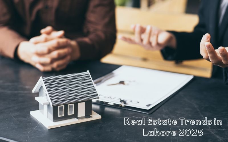 Two property dealers discussing real estate trends in Lahore 2025 with a model house and contract on the table.
