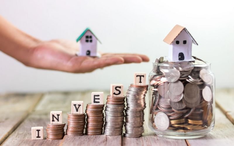 Real estate investment concept with miniature houses and coins symbolizing property investment in DHA Rahbar Phase 2.