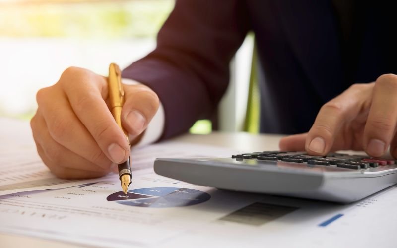 Businessman analyzing financial data with calculator and charts related to cement manufacturing plant construction in Pakistan.