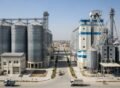 Modern grain rice and flour mill construction in Lahore with steel silos, processing units, and trucks operating on site.