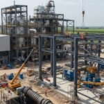 Sugar mill construction site in Pakistan showing steel framework, cranes, and workers assembling a modern industrial plant.