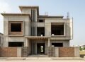 Grey structure construction in Islamabad showing a modern double storey house with concrete frame, brick walls, and roof slab under development