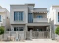 Modern grey two-story house with a balcony and decorative gate, representing House Construction in Bahria Town Islamabad.