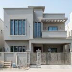 Modern grey two-story house with a balcony and decorative gate, representing House Construction in Bahria Town Islamabad.