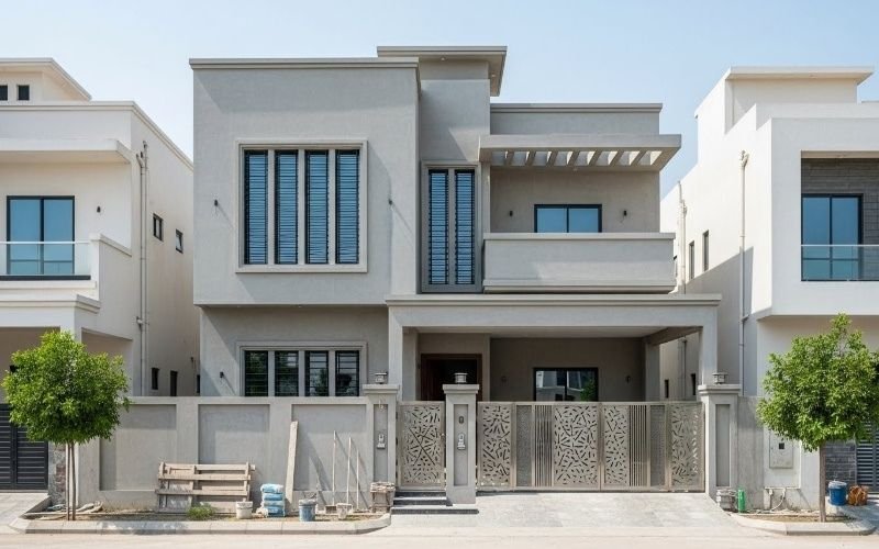 Modern grey two-story house with a balcony and decorative gate, representing House Construction in Bahria Town Islamabad.