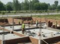 Construction workers laying foundation and brickwork during the new home building process at an early residential construction stage.