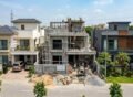 Modern double-story house under construction with workers on site showing Grey Structure Construction in Bahria Orchard Lahore surrounded by completed luxury homes.