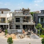 Modern double-story house under construction with workers on site showing Grey Structure Construction in Bahria Orchard Lahore surrounded by completed luxury homes.