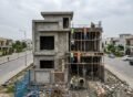 Grey Structure Construction in Bahria Town Lahore showing a multi-story house under construction with workers building columns and slabs on a residential plot.