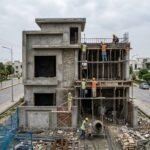 Grey Structure Construction in Bahria Town Lahore showing a multi-story house under construction with workers building columns and slabs on a residential plot.