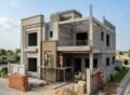 House construction site in Bahria Orchard Lahore showing a modern grey structure building under development with workers applying finishing work, scaffolding, bricks, and cement materials around the site, representing ongoing House Construction in Bahria Orchard Lahore.