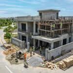 Modern grey structure house construction in Bahria Town Lahore with workers, scaffolding, and construction materials at a residential site