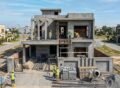 Modern double-story home under construction in a residential area, showing workers, scaffolding, and building materials during a House Construction in Lake City Lahore project.