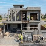Modern double-story home under construction in a residential area, showing workers, scaffolding, and building materials during a House Construction in Lake City Lahore project.