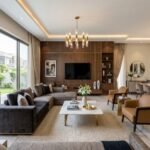 Modern luxury living room showcasing elegant Furniture Solutions in Fazaia Housing Scheme Lahore with stylish sofas, wooden TV wall, dining area, and premium interior design.