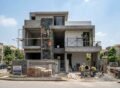 Modern under-construction house showing Grey Structure Construction in DHA Lahore with workers, scaffolding, and ongoing finishing work on a contemporary building exterior.