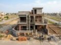 House Construction in Jubilee Town Lahore showing a modern residential building under construction with workers, scaffolding, and brickwork in progress.