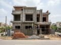 House Construction in Park View City Lahore showing a modern residential building under construction with workers, scaffolding, bricks, and cement materials on site.
