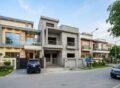 Modern house construction in T&T Aabpara Housing Society with stylish front elevations and parked cars, showcasing House Construction in T&T Aabpara Housing Society.